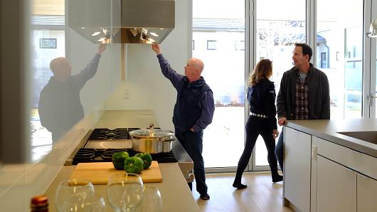 Matthew Staver | Bloomberg | Getty Images -&nbsp;Prospective buyers with their real estate agent survey the kitchen of a new home.